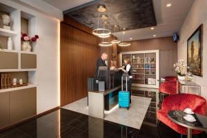 a man and a woman standing at a counter in a lobby at Dharma Luxury Hotel in Rome