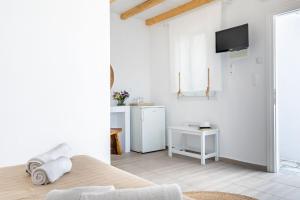 a white room with a bed and a tv on a wall at Milia Beach Apartments in Paralia Milia