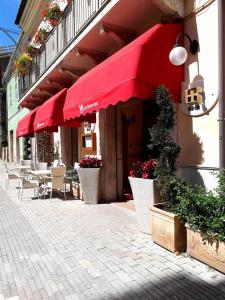 un ristorante con ombrelloni rossi, tavoli e sedie di Hotel Ristorante Da Roverino a Comunanza
