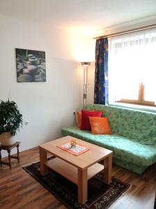 a living room with a green couch and a table at Ferienwohnung Weinbergblick in Oberrohrendorf