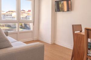Una sala de estar con un sofá y dos ventanas. en Apartamento Fisterra con vistas al mar, en Finisterre