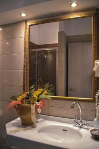 a bathroom sink with a large mirror and a vase with flowers at Nafsika Apartments in Parga