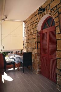 una pared de ladrillo con una mesa y una puerta roja en Nafsika Apartments en Párga