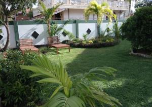 un patio con 2 bancos, palmeras y un edificio en Romeo and Juliet Guest House, en Negombo