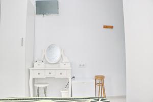 1 dormitorio con paredes blancas, espejo y taburete en Habitación Cañaveral Playa Conil I, en Conil de la Frontera