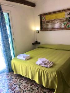 a bedroom with a green bed with towels on it at Casa Colore Attic in Castellammare del Golfo