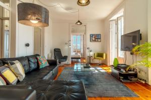uma sala de estar com um sofá de couro preto e uma televisão em LV Premier Apartments Baixa- CN em Lisboa