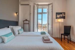 a bedroom with two beds and a chair and a window at LV Premier Apartments Baixa- CN in Lisbon