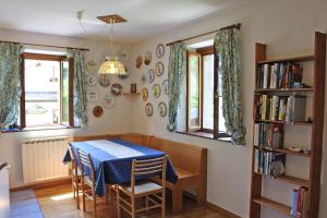 uma sala de jantar com uma mesa azul e duas janelas em Albergo Diffuso Comeglians em Comeglians