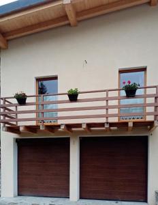 a house with a balcony and two garage doors at Casa vacanza il Granaio in La Thuile