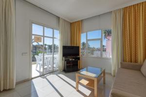 a living room with a couch and a tv at Bungalows Tisaya Golf in Maspalomas