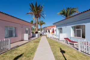 een loopbrug tussen twee huizen met palmbomen bij Bungalows Tisaya Golf in Maspalomas