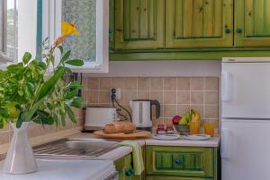 a kitchen with green cabinets and a counter top with a sink at MANESSIS Apartments Kassiopi Bay Corfu in Kassiopi
