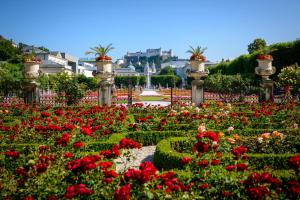 un giardino di fiori rossi con una fontana sullo sfondo di Hotel Kaiserhof ad Anif
