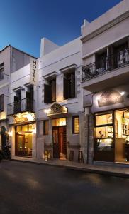 Odos Oneiron Boutique Hotel في مدينة خانيا: مبنى ابيض وامامه بعض الطاولات