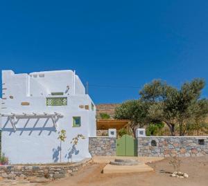 a white building with a green door in a field at Elia Traditional suites in Astypalaia Town
