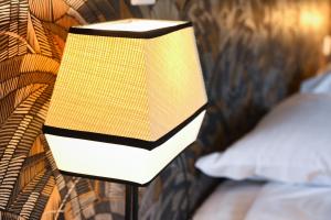 a lamp in front of a bed with a pillow at Hôtel Les Muses in Annecy