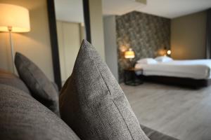 a couch with pillows in a hotel room with a bed at Hôtel Les Muses in Annecy