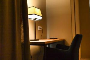 a desk with a lamp and a chair in a room at Hôtel Les Muses in Annecy