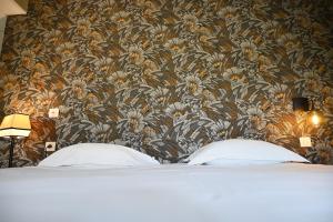 a bedroom with a floral wallpaper and a bed with two pillows at Hôtel Les Muses in Annecy