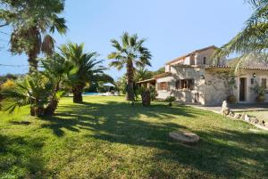 a house with palm trees in front of a yard at Mena in Pollença