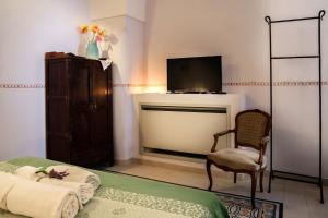 a bedroom with a bed and a tv and a chair at Le Viùzze Apartment in Tricase