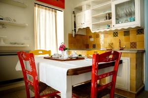 a kitchen with a table and two red chairs at Le Viùzze Apartment in Tricase