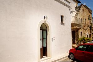 a red car parked next to a white building at Le Viùzze Apartment in Tricase