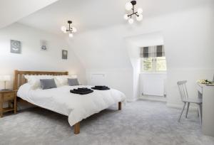 a white bedroom with a large bed and a desk at Agatha Bear Cottage in Stow on the Wold