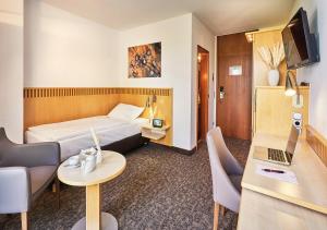 ニュームブレヒトにあるParkhotel Nümbrechtのベッド、テーブル、椅子が備わるホテルルームです。