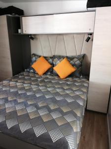 ein Bett mit zwei orangenen Kissen in einem Zimmer in der Unterkunft Mobile Home Mali raj in Biograd na Moru