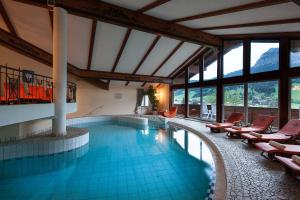 una piscina en un hotel con sillas y ventanas en Hotel Schwarzer Adler mit Vilsalpsee Bähnchen, en Tannheim