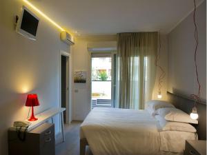 una camera da letto con un letto, una scrivania e una finestra di Hotel Parco a Milano Marittima