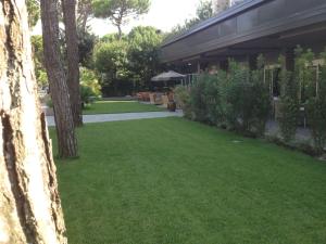 un patio con césped verde y árboles y un edificio en Hotel Parco, en Milano Marittima