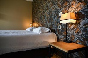 a hotel room with a bed and a table with a lamp at Hôtel Les Muses in Annecy