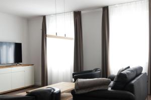 a living room with black leather furniture and a television at Villa Insel in Börgerende-Rethwisch