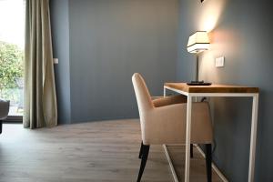 a room with a desk with a chair and a lamp at Hôtel Les Muses in Annecy
