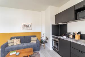 a living room with a couch and a kitchen at Les Carmélites - Appartements dans l'hyper-centre de Rennes in Rennes