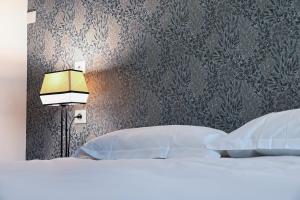 a bedroom with a bed with a lamp and a wall at Hôtel Les Muses in Annecy