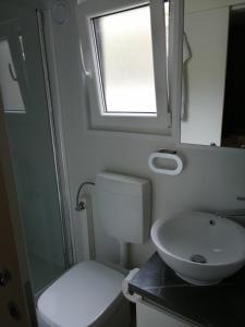 ein Bad mit einem Waschbecken, einem WC und einem Fenster in der Unterkunft Mobile Home Mali raj in Biograd na Moru