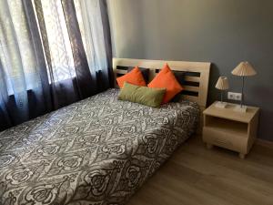 a bedroom with a bed with orange and green pillows at VP APARTMENTS in Sillamäe