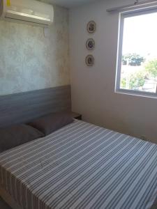 ein Schlafzimmer mit einem großen Bett mit Fenster in der Unterkunft Apartamentos Brisa del Mar in Luis Correia