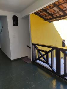 a room with a yellow wall and a wooden railing at Suites Mar Azul Prainha in Arraial do Cabo