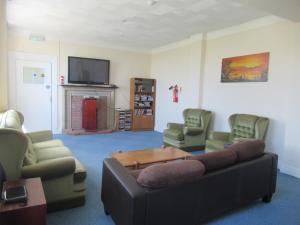 a living room with a couch and chairs and a tv at Foreshore House in New Romney