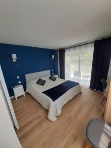 1 dormitorio con 1 cama grande y pared azul en LA COTTINIERE, en Drefféac