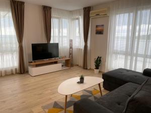 a living room with a couch and a tv at Sea Тerrace Aquamarine in Golden Sands