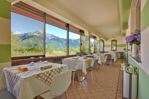 Hotel Europa - Sorico في سوريكو: مطعم فيه طاولات وكراسي فيه جبال في الخلف