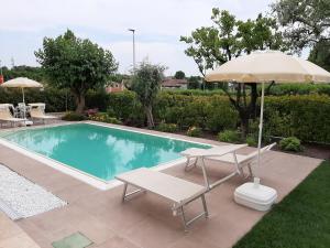 ein Pool mit einem Sonnenschirm, 2 Stühlen, einem Tisch und einem Sonnenschirm in der Unterkunft Villa Luisa Rooms&Breakfast in Peschiera del Garda