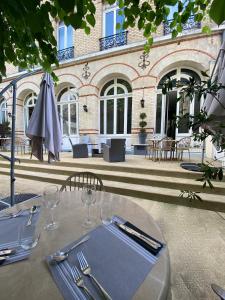 a table with a napkin and glasses and an umbrella at Hôtel Concordia Le Mans Centre Gare in Le Mans