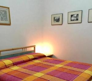 um quarto com uma cama colorida com três fotografias na parede em Appartamento vista mare Maya 2 em Costa Paradiso